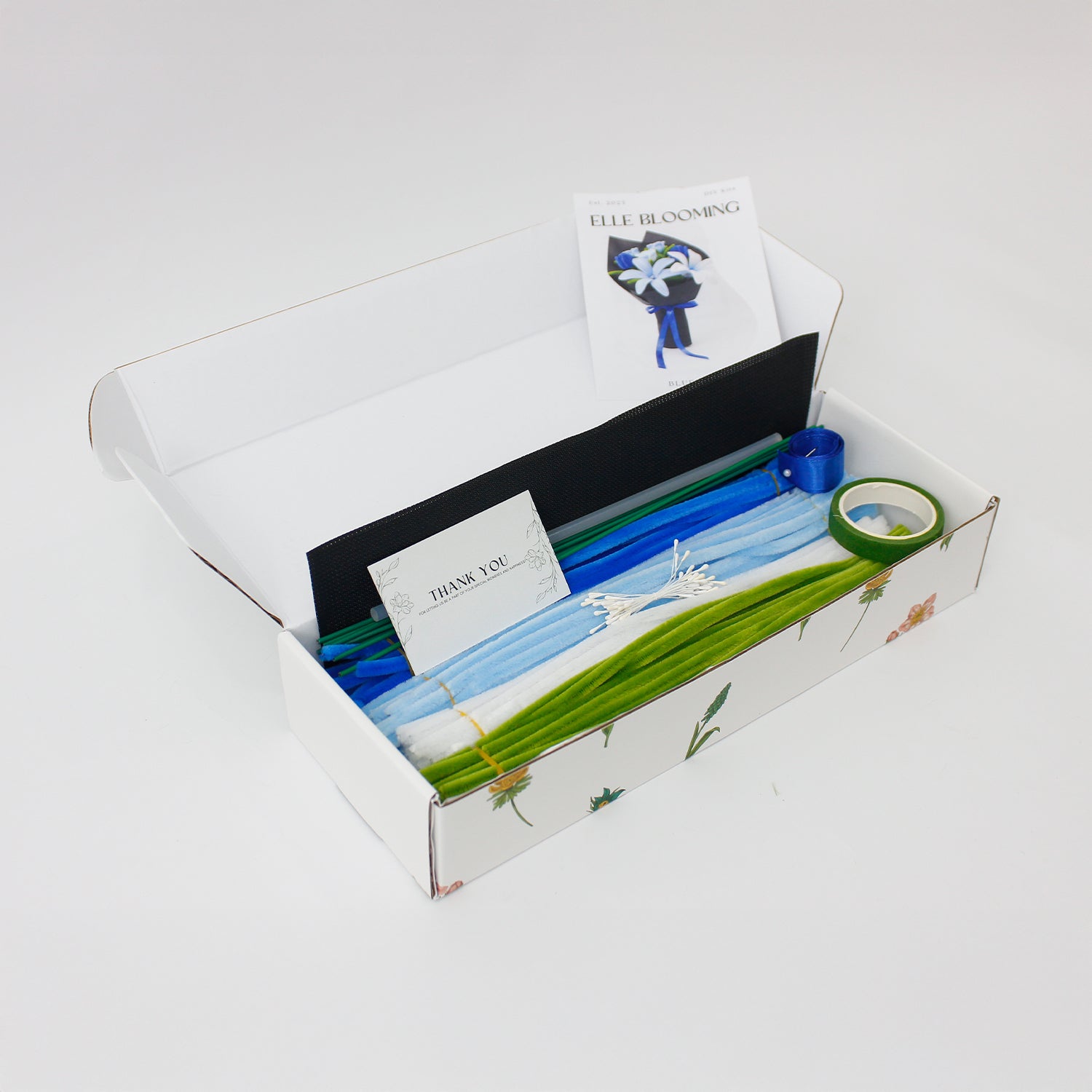 Bluence DIY bouquet with handmade blue, white, and light blue lilies crafted from pipe cleaners. Wrapped in sleek black paper with a royal blue ribbon, this elegant DIY floral kit is perfect for unique gifts and calming creative projects.