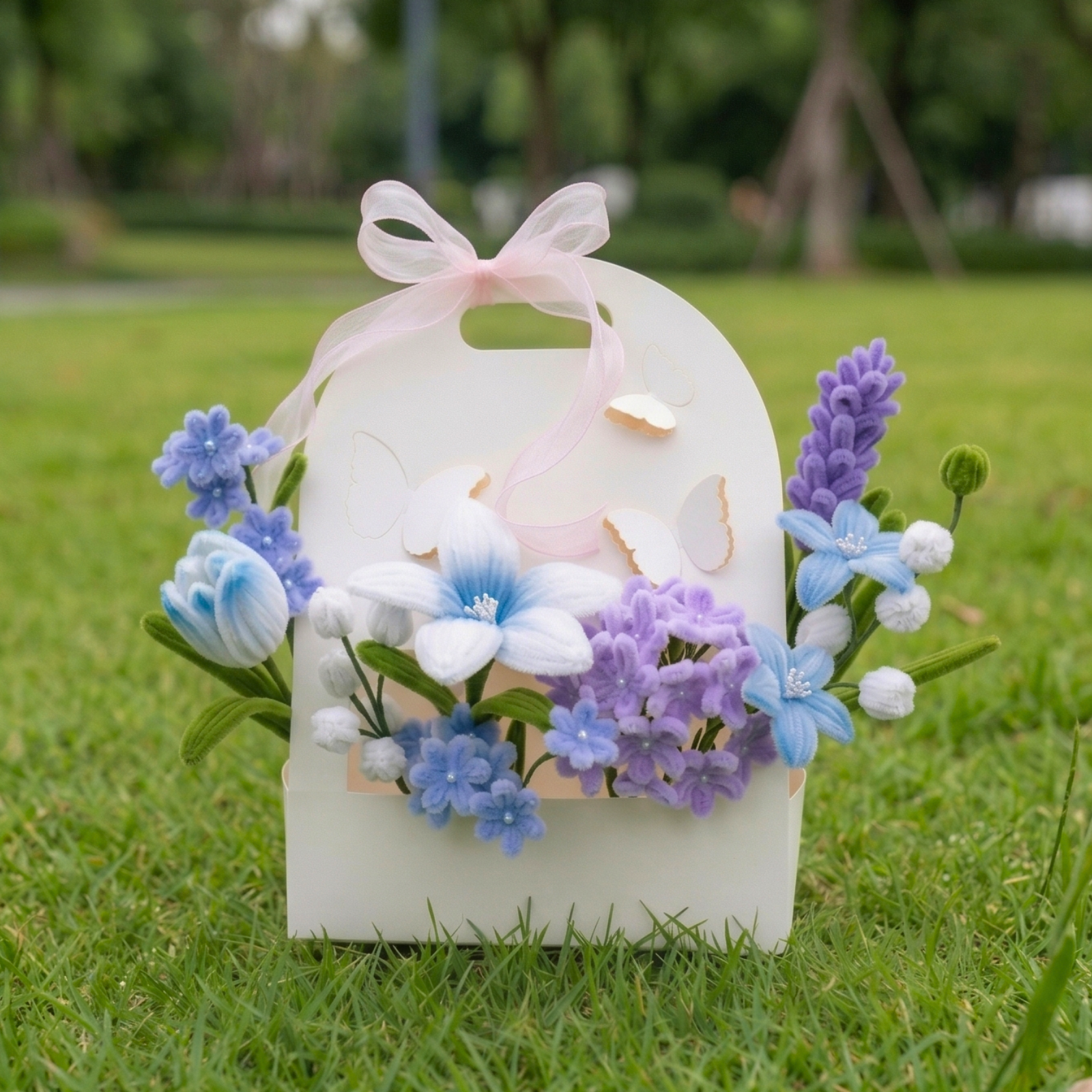 Decorative box with flowers and a pink bow on grass