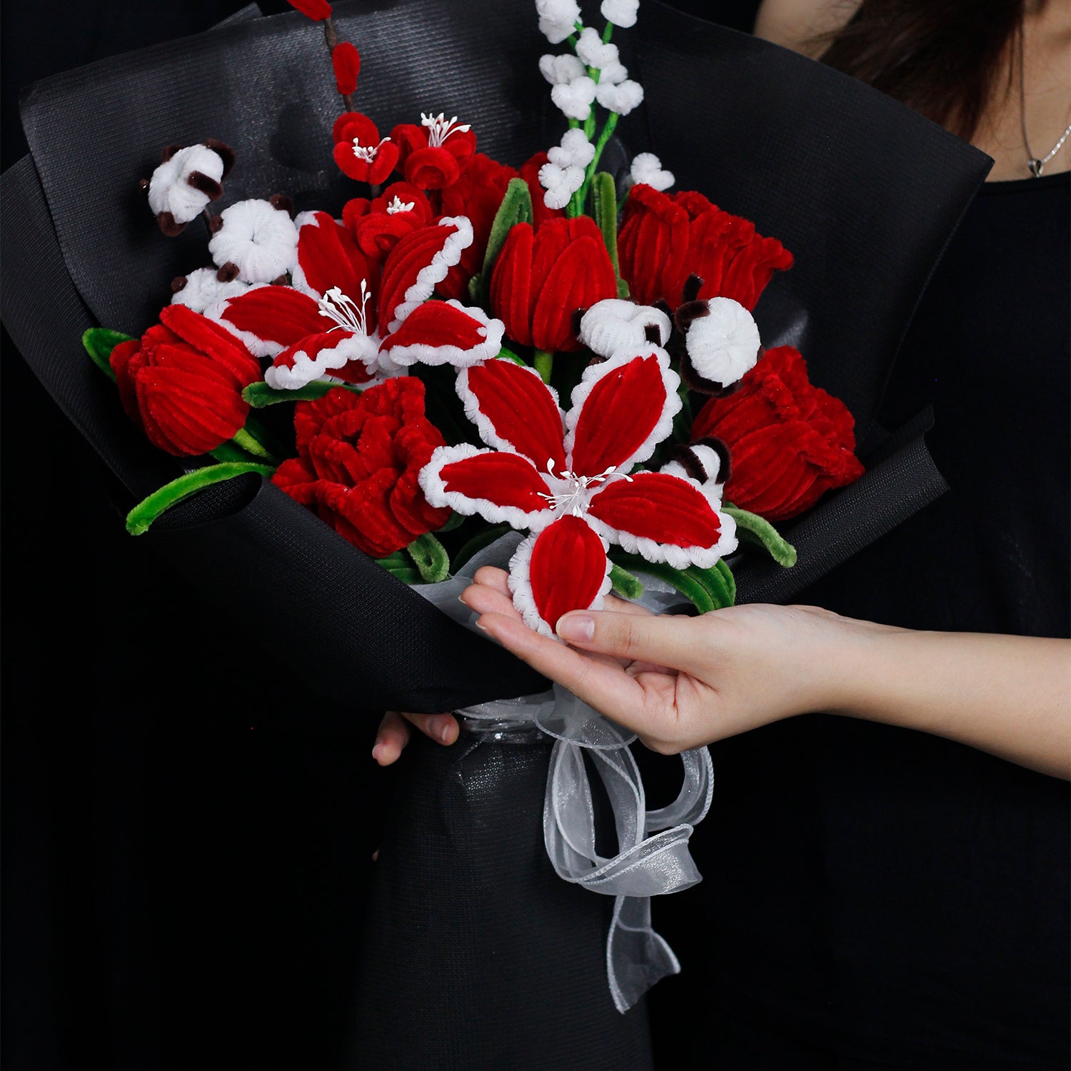 Red and white handmade pipe cleaner bouquet wrapped in festive Christmas paper with red bow. Features poinsettia-inspired flowers and snowflake accents. Ideal for holiday gifts.