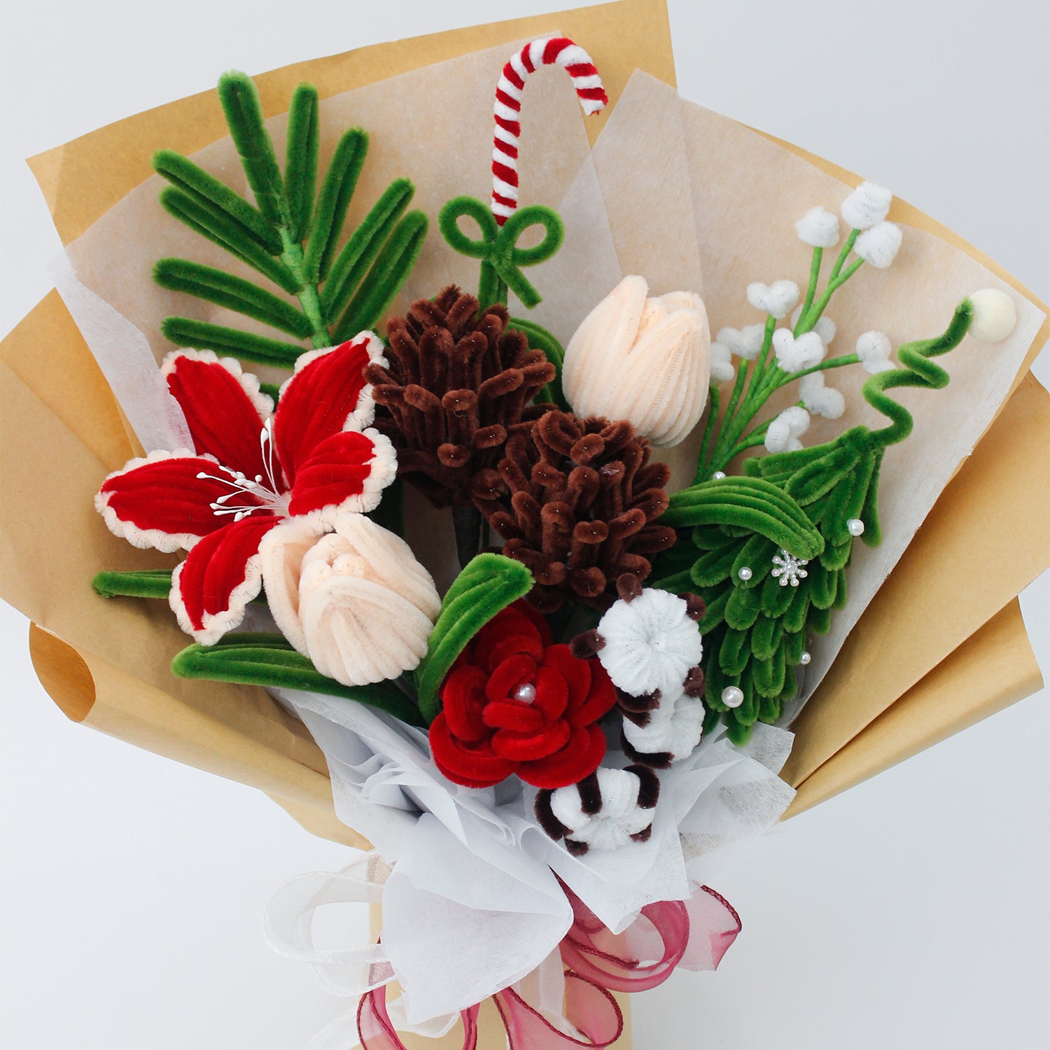DIY flower bouquet kit "Winter Whispers" featuring handmade pinecones, red lily, candy cane, tulips, and cotton flowers made from pipe cleaners. Perfect for Christmas crafting or gifting.