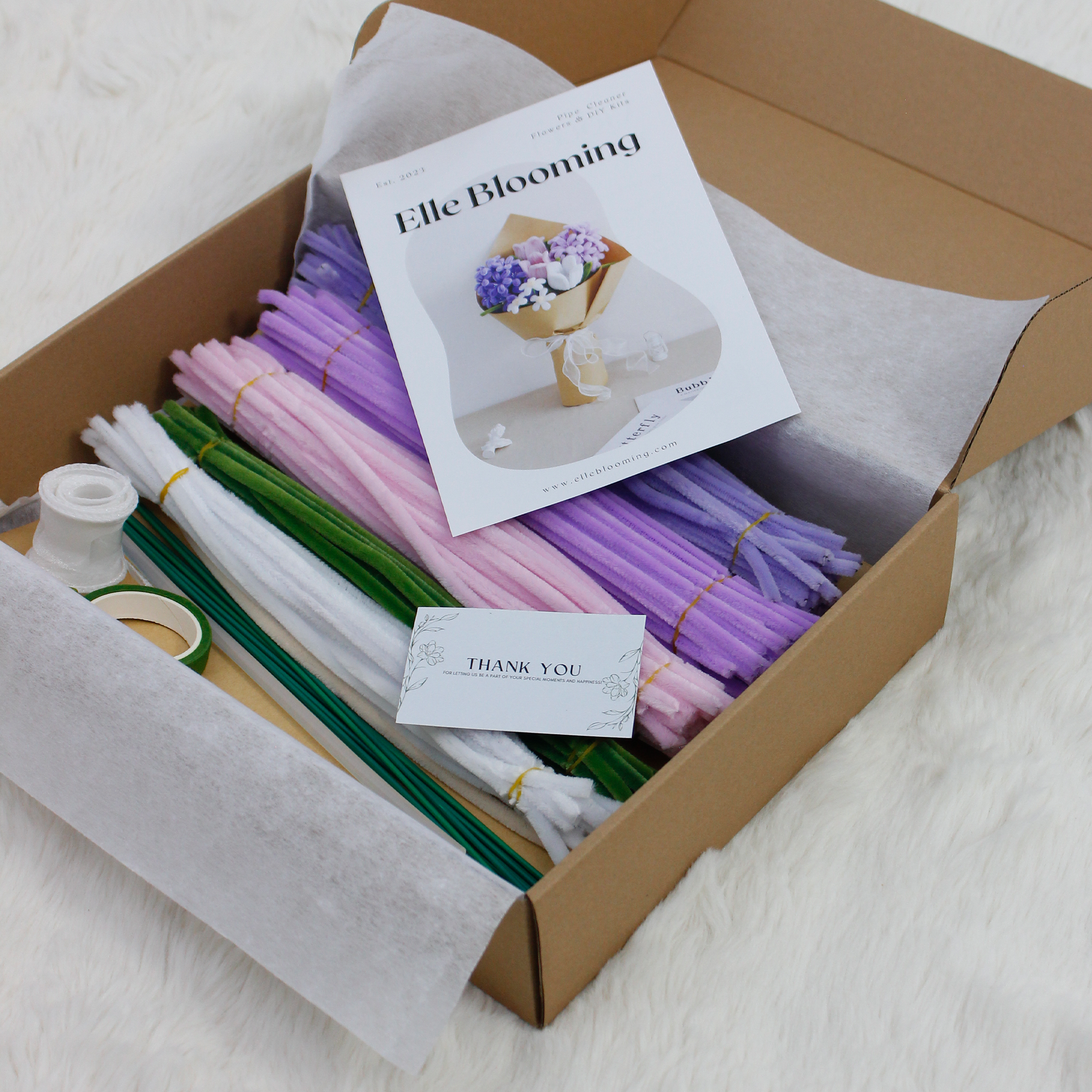 Elegant DIY kit featuring a bouquet of violet, pink, and white pipe cleaner flowers, complete with crafting materials and gift-ready packaging.

