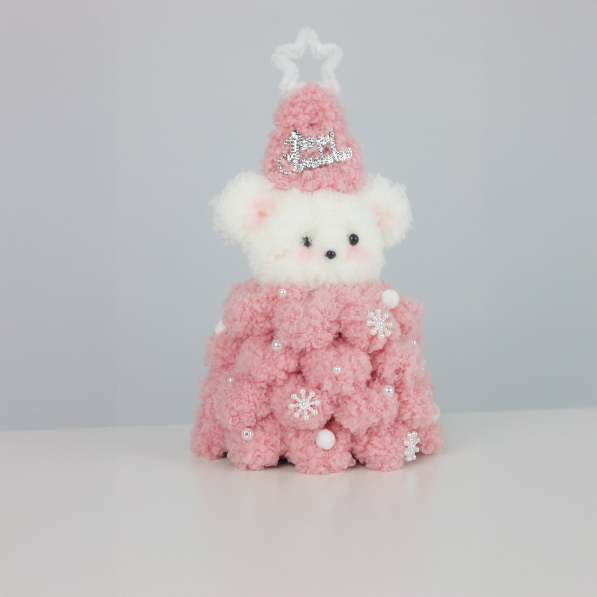 Soft pink Christmas bear wearing a fuzzy star hat and textured pipe cleaner dress with pearl snowflakes – a sweet DIY decor or gift for the holiday season.