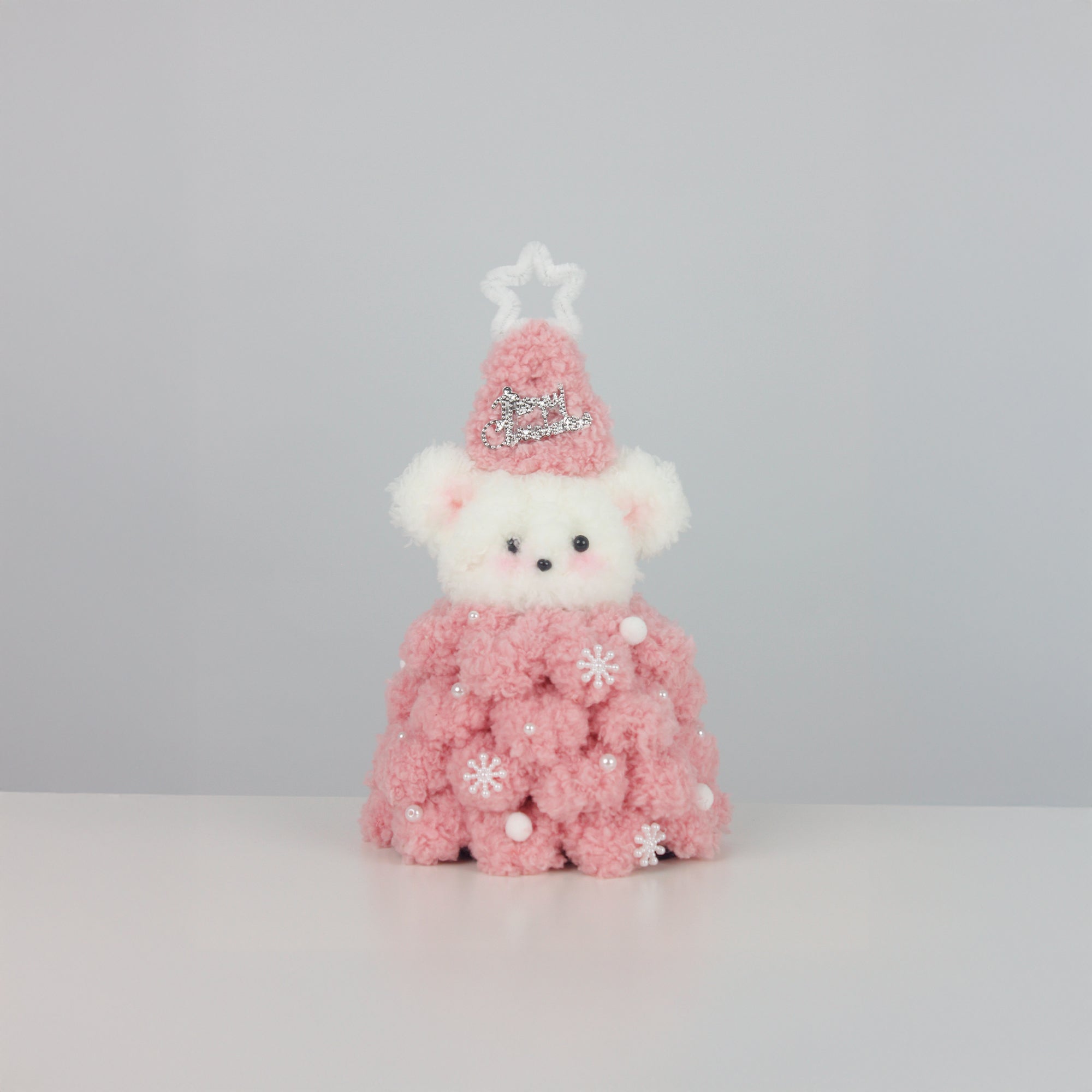 Soft pink Christmas bear wearing a fuzzy star hat and textured pipe cleaner dress with pearl snowflakes – a sweet DIY decor or gift for the holiday season.
