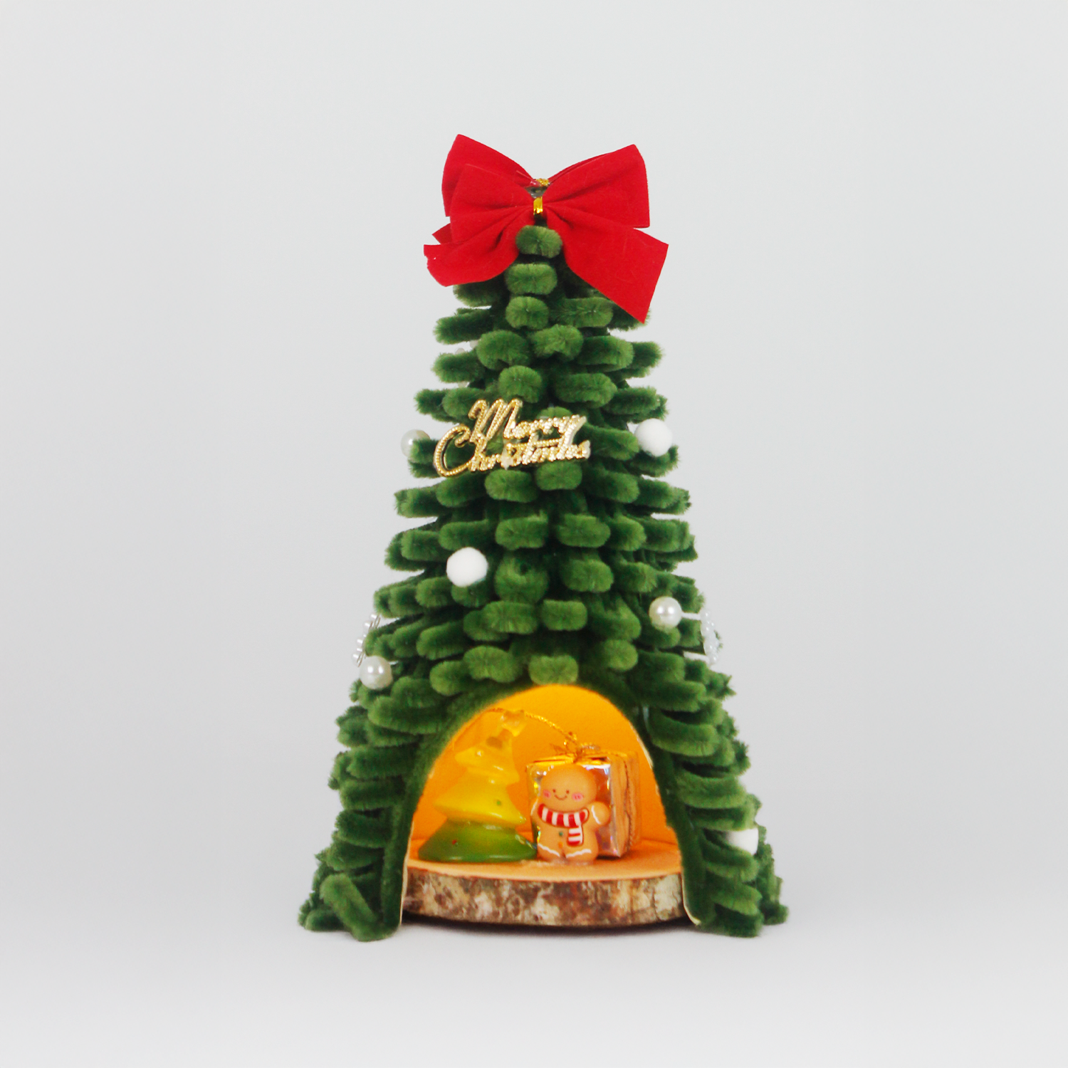 Unique handmade Christmas tree cabin crafted from green pipe cleaners, with lights and gingerbread decor – cozy holiday display.