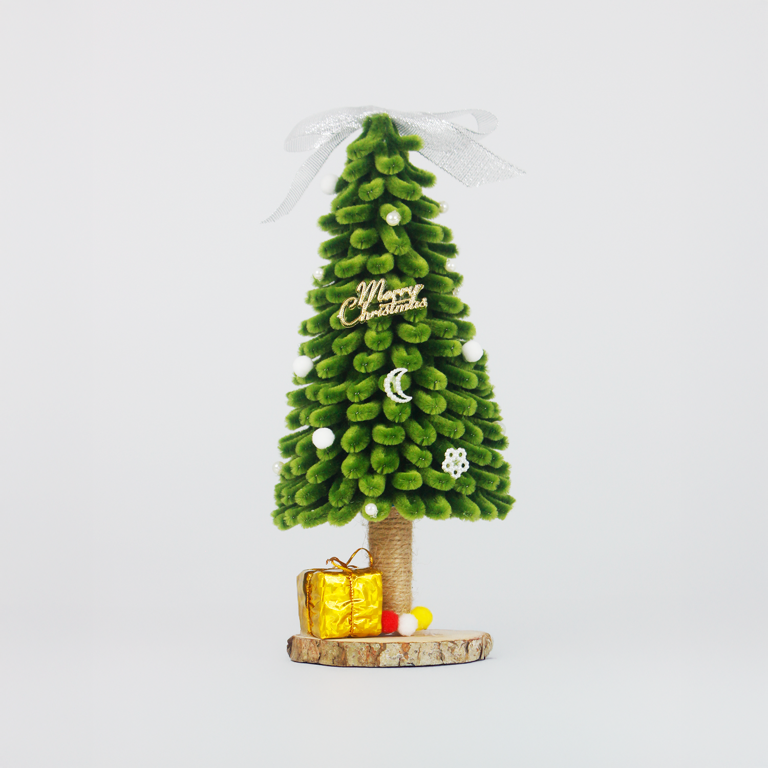 Green pipe cleaner Christmas tree with silver ribbon, mini ornaments, pom-poms, and golden gift box on rustic wood base – perfect handmade holiday decor or DIY Christmas gift
