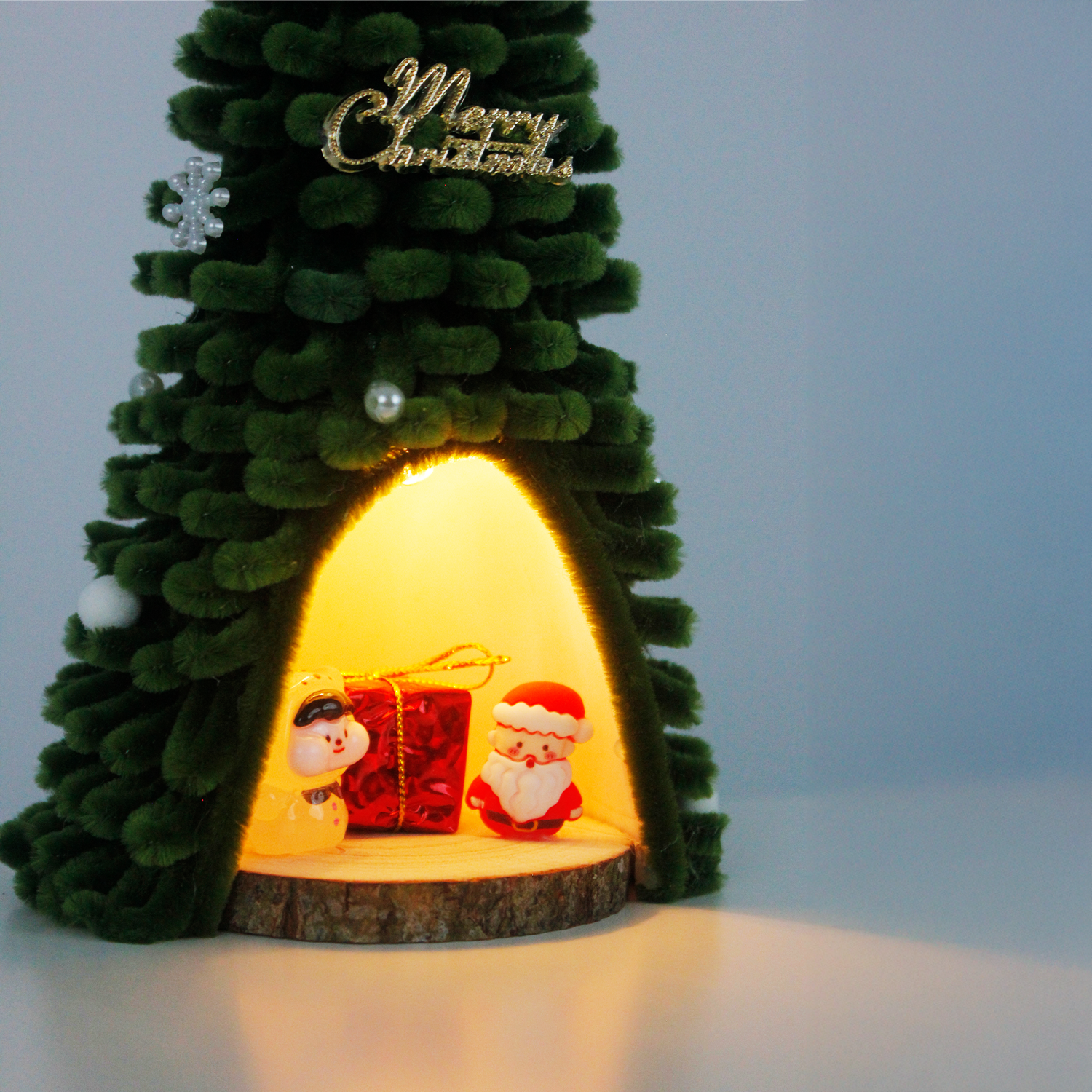Green fuzzy wire Christmas tree featuring Santa Claus and pig figurine inside, topped with red bow – unique and charming holiday decor